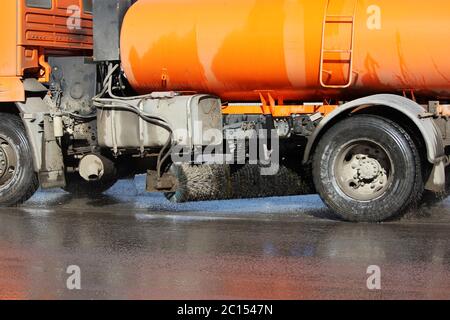 Orange Erntemaschine wäscht Autostraße im Frühjahr. Stockfoto