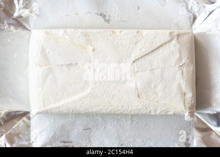 Nahaufnahme Folienverpackung und gefrorenes weißes Eis, Draufsicht Stockfoto