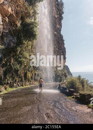 Wasserfall in der Natur auf der portugiesischen Insel Madeira Road. Der Mann, der unter dem Wasserfall badende. Stockfoto