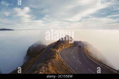 Fantastischer traumhafter Sonnenaufgang auf felsigen Bergen mit Blick in das neblige Tal. Neblige Wolken über Wald. Blick unten auf die Landschaft der Fee. Stockfoto