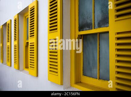 Fenster mit hellgelben Fensterläden. Stockfoto