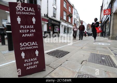 Die Menschen gehen an einem sozialen Distanzierungsschild in der Hauptstraße in Winchester vorbei, bevor am 15. Juni die nicht unbedingt notwendigen Einzelhändler in England wieder eröffnet werden. Stockfoto