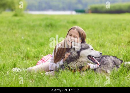 Happy Little girl Kind mit einem Husky Hund spielt in der Natur. Stockfoto