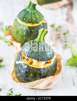 Drei Zucchini gefüllt mit Burgul und Hühnerfleisch mit Kräutern und reifenden Käse. Stockfoto