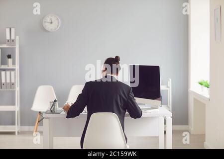 Ein Mann in einem schwarzen Anzug sitzt am Tisch arbeitet mit Papieren im Büro. Stockfoto