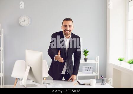 Handshake-Angebot. Ein Geschäftsmann bietet einen Handschlag, während er in einem Büro steht. Stockfoto