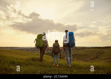 Familie mit Rucksäcken. Touristen stehen in der Natur Wandern am Abend in der Nacht. Rückansicht. Stockfoto