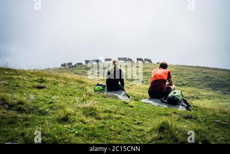 Paar Mann und Frau sitzen genießen Berge und Wolken Landschaft. Liebe und reisen glückliche Emotionen. Lifestyle-Konzept Stockfoto
