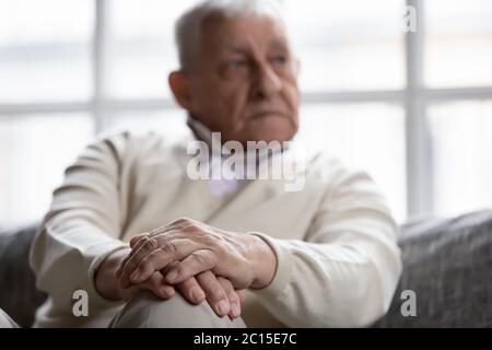 Nahaufnahme nachdenklicher älterer Mann, der mit gefalteten Händen sitzt Stockfoto