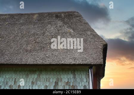 Haus mit Strohdach bei Sonnenuntergang Stockfoto