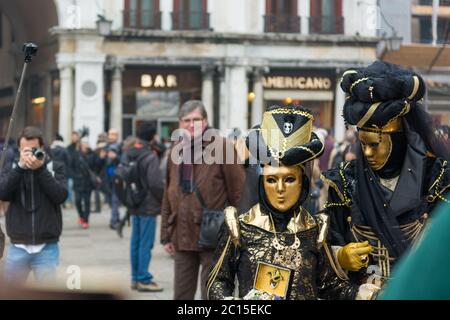 Venedig, Italien - 30. Januar 2016: Piazza San Marco oder Markusplatz in Venedig - schöne Masken posieren mit Touristen Stockfoto