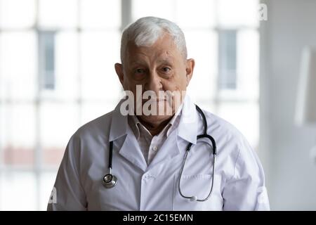 Kopf geschossen Porträt älteren Arzt trägt weiße Uniform mit Stethoskop Stockfoto