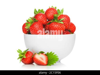 Frische rohe Bio-Erdbeeren in weißer Keramik-Schüssel auf weißem Hintergrund mit Beeren daneben. Makro Stockfoto