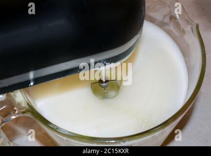 Nahaufnahme eines Mixers, der Zutaten in einer Glasschüssel aufpeitscht. Stockfoto