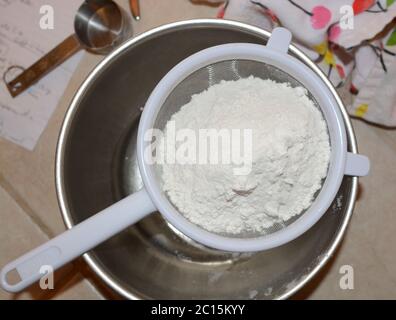 Ein Metallsiebfilter zum Sieben von Zutaten in eine Schüssel. Backen in der Küche. Nahaufnahme. Stockfoto