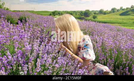 Porträt einer lächelnden jungen Frau, die Blumen riecht auf dem Lavendelfeld in der Provence Stockfoto