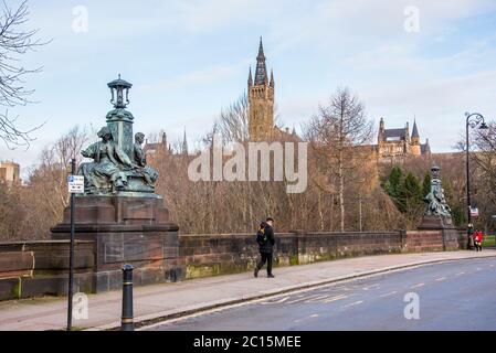 Zwei der Skulpturen auf der Kelvin Way Bridge blicken auf den Turm des Gilbert Scott Building der Glasgow University.