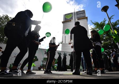 Menschen lassen Ballons in der Grenfell Memorial Community Mosaic am Fuße des Tower Blocks in London zum dritten Jahrestag des Grenfell Tower-Feuers, der am 14 2017. Juni 72 Menschenleben forderte, frei. Stockfoto