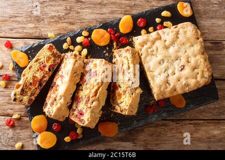 Gesunde Ernährung Obstkuchen mit getrockneten Aprikosen Beeren Rosinen Feigen Kirschen Closeup auf einem Schieferbrett auf dem Tisch. Horizontale Draufsicht von oben Stockfoto