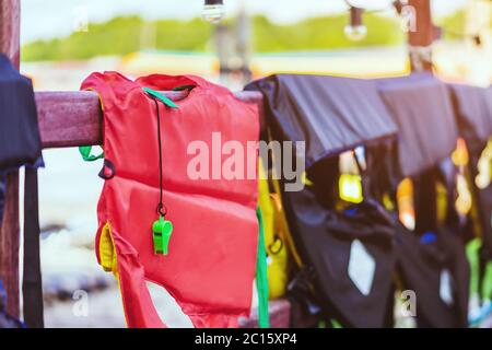 Eine grüne Pfeife mit roter Lebensjacke, die am Geländer um den Gehweg hängt, damit die Passagiere sicher an den Docks sind. Stockfoto