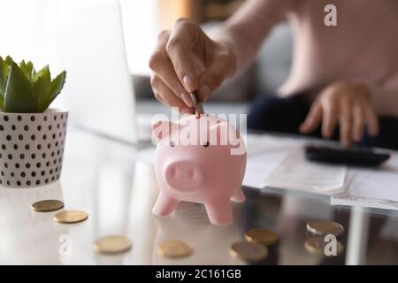 Nahaufnahme Frau, die Münze in Sparschwein legt, Rechnungen berechnet Stockfoto