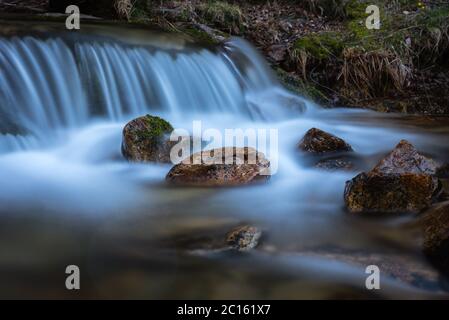 Flusswasser fällt von einem kleinen Wasserfall und zwischen den Felsen, Rascafría, Madrid, Spanien Stockfoto