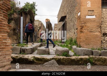 Ein Besucher der antiken Stadt Pompeji geht über Trittsteine, die von Fußgängern benutzt werden, um Straßen zu überqueren, ohne in sie hinabzusteigen. Italien Stockfoto