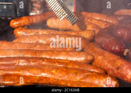 Grillen verschiedener Wurstsorten, trockenes und frisches Fleisch auf einem offenen Grill Stockfoto