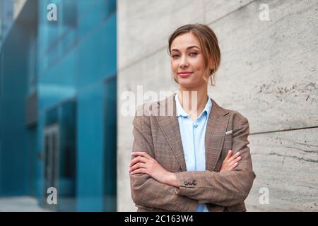 Geschäftsfrau erfolgreiche Frau Business Person stehend Arme gekreuzt Outdoor-Unternehmensgebäude außen nachdenkliche Eleganz kaukasischen Vertrauen bekennen Stockfoto