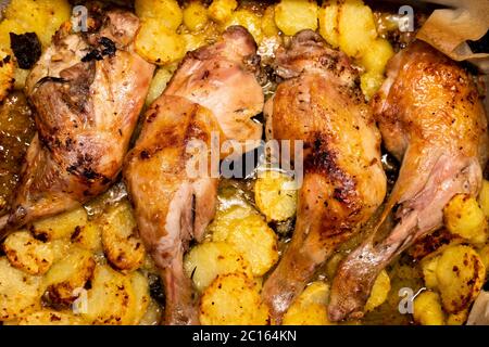 Gebratene Hähnchenschenkel in einer Pfanne, gegart und mit Kartoffelscheiben garniert. Draufsicht, Nahaufnahme, Vollformat. Stockfoto