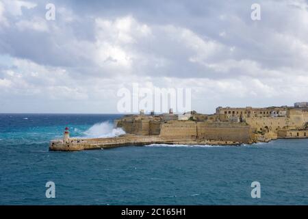 VALLETTA, MALTA - 31. DEZEMBER 2019: Blick von Fort St Elmo auf den Ricasoli Grand Harbour East Breakwater und roten Leuchtturm bei starken Wellen Stockfoto