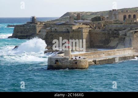 VALLETTA, MALTA - 31. DEZEMBER 2019: Blick von Fort St Elmo auf den Ricasoli Grand Harbour East Breakwater und roten Leuchtturm bei starken Wellen Stockfoto