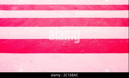 Zebra Fußgängerüberweg mit Leuchtfarbe gemalt, weiße Fahrrad-Fahrbahnmarkierungen auf rotem Hintergrund, Blitzgerät Kunstlicht. Stockfoto