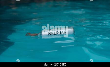 HILF MIR Nachricht geschrieben auf einem weißen Papier in der Glasflasche schwimmt in blauem Wasser in der Mitte des Meeres Stockfoto