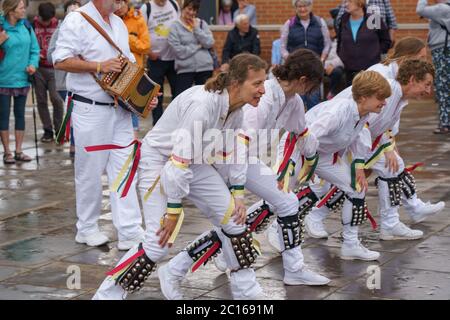 Morris-Tänzer, die in weiß gekleidet sind und Knieglocken und farbige Bänder tragen, tanzen an der Strandpromenade der Folk Week in Whitby, North Yorkshire, Großbritannien. Stockfoto