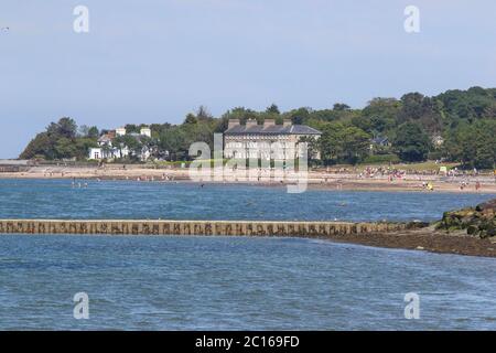 Holywood, County Down, Nordirland. 14. Juni 2020. Wetter in Großbritannien - ein warmer sonniger Tag an der Küste von Belfast Lough in der nahe gelegenen Stadt Holywood hat Leute gesehen, die versuchen, das schöne sonnige und warme Wetter mit Temperaturen in der Mitte der zwanziger Jahre zu genießen. Die Menschen waren nach der Lockerung der Sperrungsbeschränkungen am Kiesstrand von Holywood County Down weit entfernt. Kredit: CAZIMB/Alamy Live Nachrichten. Stockfoto