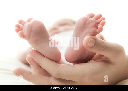 Die Hand der Mutter hält die Beine Stockfoto