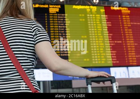 Frau schaut sich die Anzeigetafel am Flughafen an. Wählen Sie ein Land Belgien für Reisen oder Migration. Stockfoto