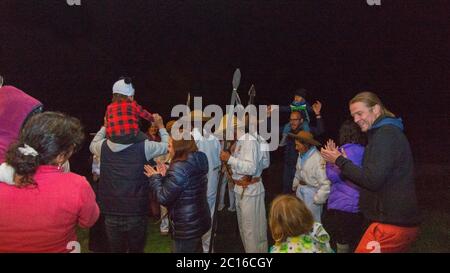 Quito, Pichincha / Ecuador - Februar 16 2019: Indigene Frau in typischen Kostümen und indigene Männer tanzen im Kreis mit Touristen auf einem b Stockfoto