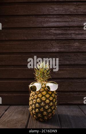 Diese coole Ananas verbreitet Sommerurlaub Vibes mit seiner stilvollen Sonnenbrille und dunklen Holzhintergrund. Hochwertige Fotos Stockfoto