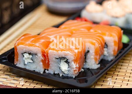 Sushi rollt auf einem Plastikteller. Lieferung von asiatischen Lebensmitteln nach Hause. Stockfoto