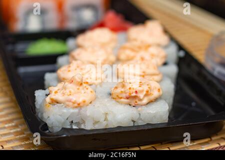 Sushi rollt auf einem Plastikteller. Lieferung von asiatischen Lebensmitteln nach Hause. Stockfoto