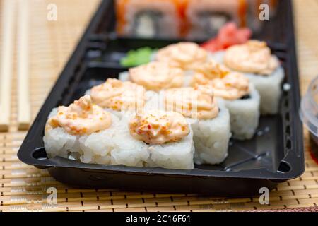 Lieferung von asiatischen Lebensmitteln nach Hause. Sushi rollt auf einem Plastikteller. Stockfoto