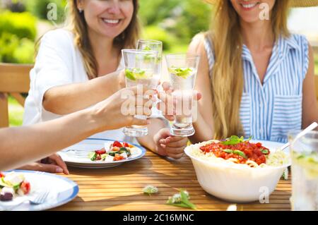 Gerne weibliche Freunde mit Gläser limonade am Esstisch in Rasen Stockfoto