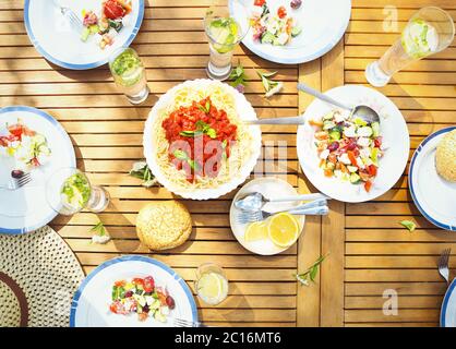 Familienessen Auswahl an italienischen Gerichten auf Holztisch im Garten Stockfoto