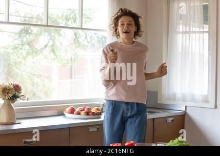 Glückliche junge Frau haben Spaß beim Kochen zu Hause Stockfoto