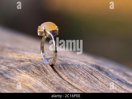 Verlobungsring mit cremig gelb orange Chalcedon Achat Edelstein auf Holz. Chalcedonsteine gibt es in verschiedenen Farben und sind in der Regel pol Stockfoto