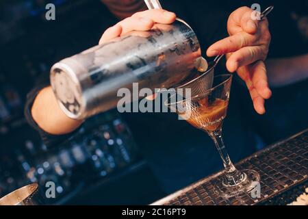 Barkeeper Gießen mit Sieb White gesund Cocktail Drink auf einer Theke. Professionelle Ansicht . Trendy stilvolle alkoholische Getränke . Design People A Stockfoto