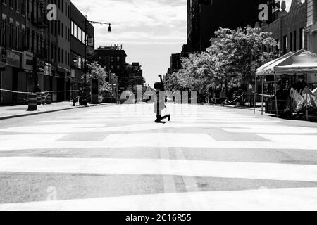 New York, NY - 14. Juni 2020: Eine Frau mit #BLM-Shirt posiert mit geballter Hand auf Fulton Street gemalt riesigen Black Lives Matter Slogan während der Enthüllung Zeremonie in Bedford-Stuyvesant Stockfoto