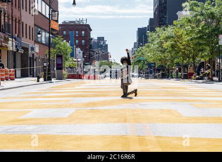 New York, Usa. Juni 2020. Eine Frau, die #BLM Hemd trägt, posiert mit geballter Hand auf der Fulton Straße, gemalt riesigen Black Lives Matter Slogan während der Enthüllungszeremonie in Bedford-Stuyvesant Nachbarschaft von Brooklyn in New York am 14. Juni 2020. Das fertige Wandbild erstreckt sich von Marcy Avenue bis New York Avenue für 375 Fuß. (Foto von Lev Radin/Sipa USA) Quelle: SIPA USA/Alamy Live News Stockfoto